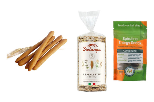 Grissini, gallette ai cereali e snack alla spirulina su sfondo bianco, idee per merende sane
